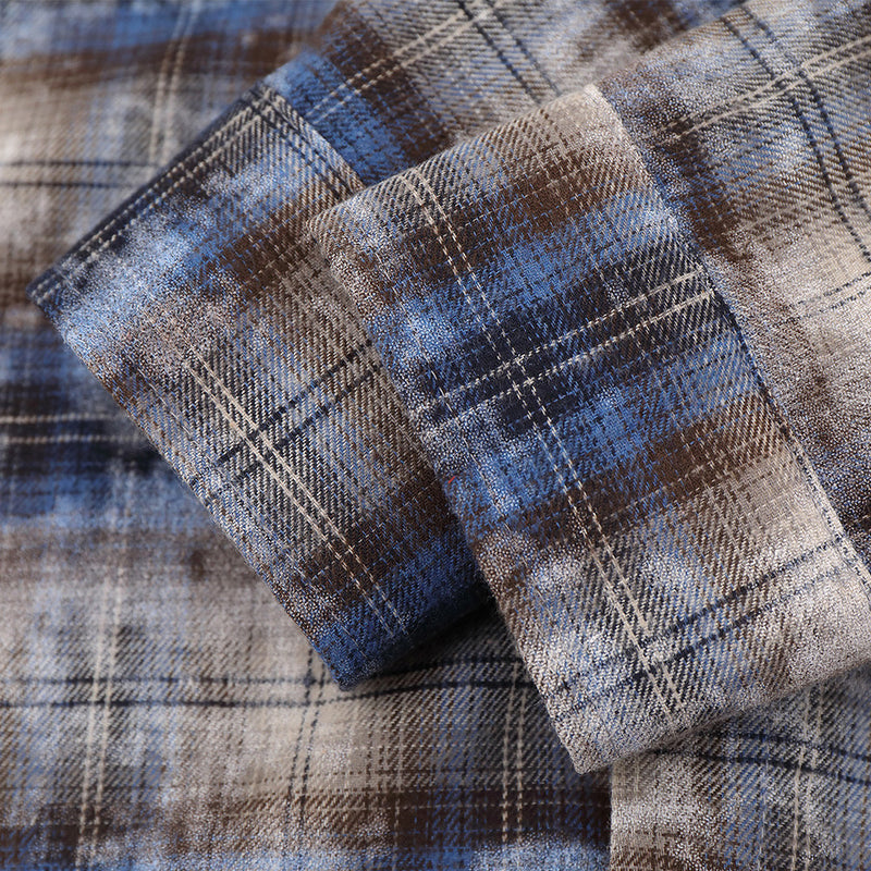 Close-up of cuffed sleeve detail on blue plaid shirt