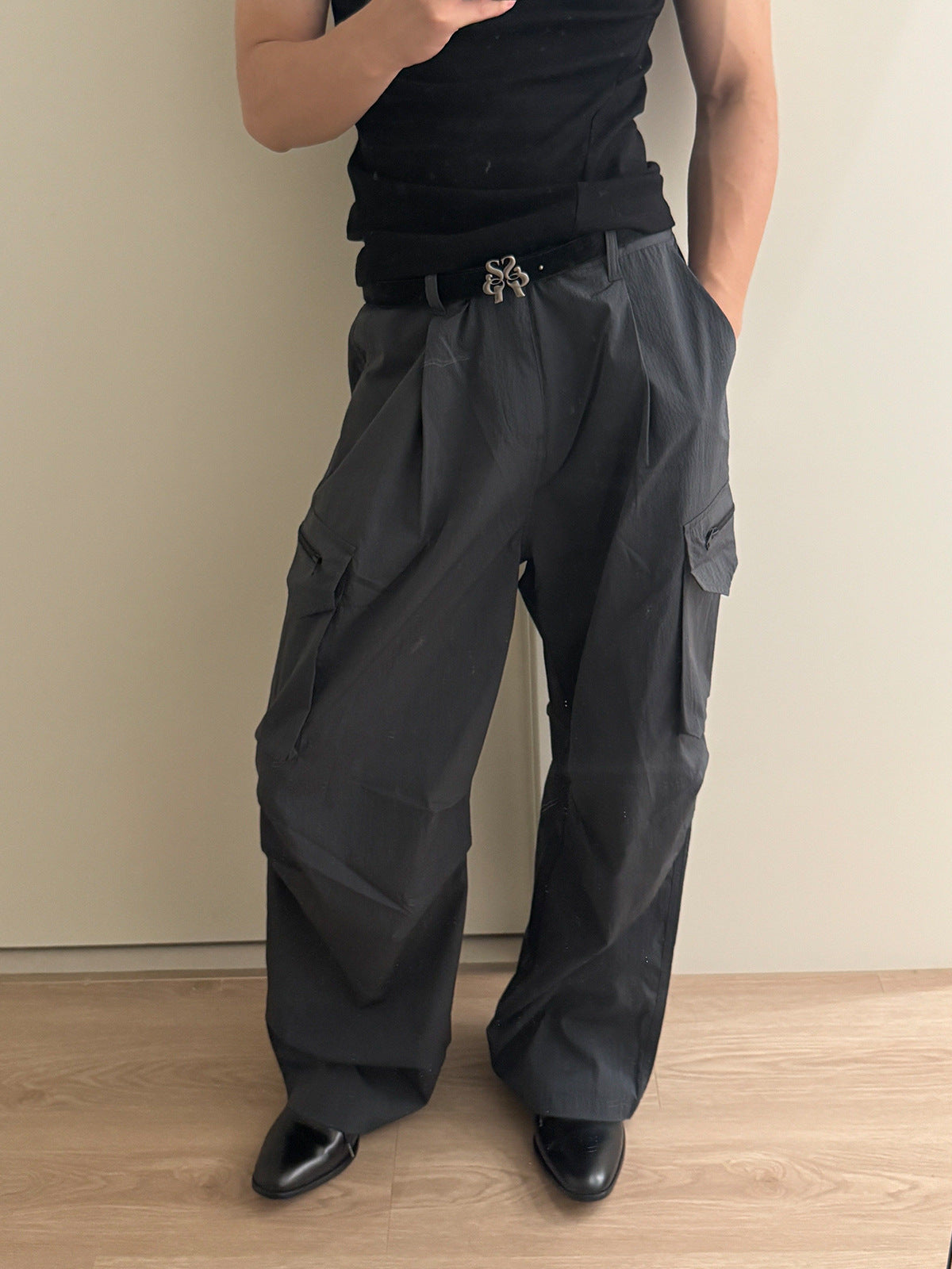 Wide-leg ripstop nylon cargo pants with zipper pockets and large flap thigh pockets in charcoal grey and black