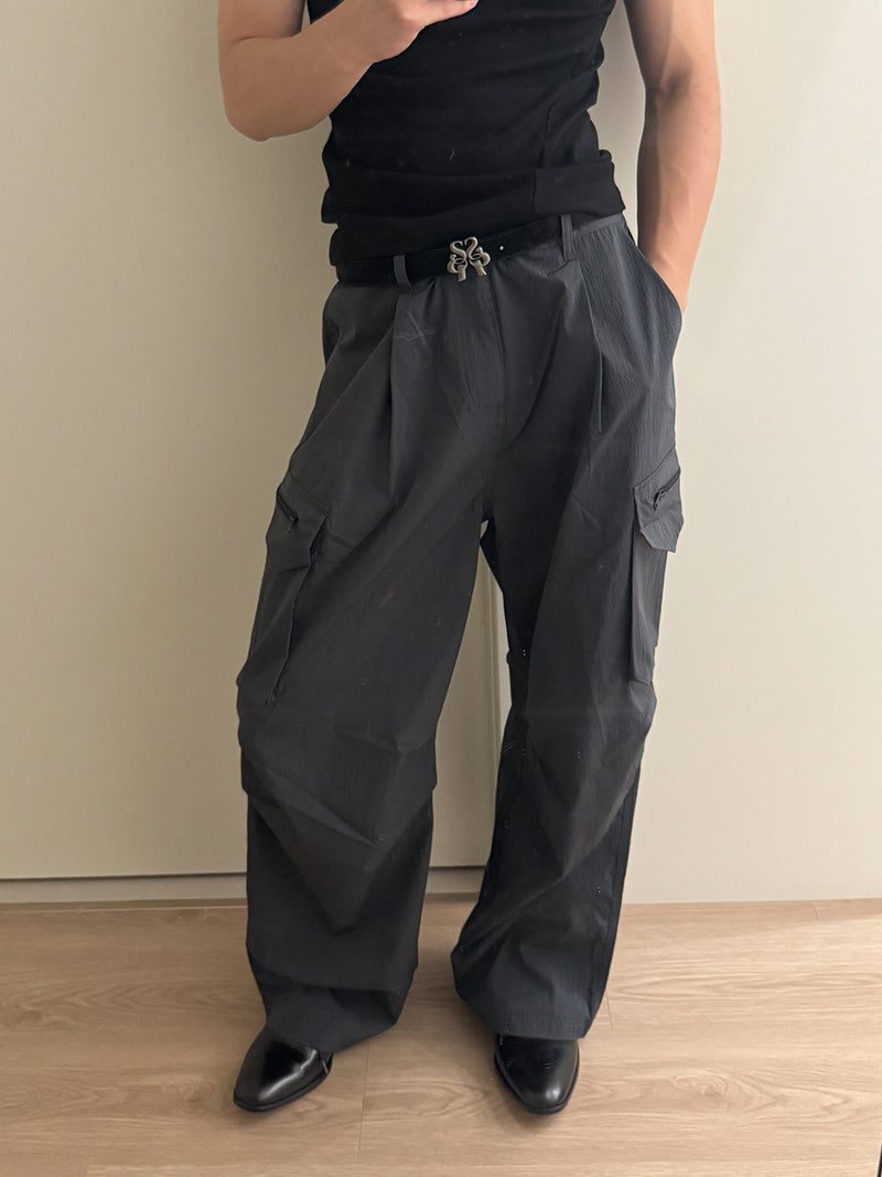 Wide-leg ripstop nylon cargo pants with zipper pockets and large flap thigh pockets in charcoal grey and black