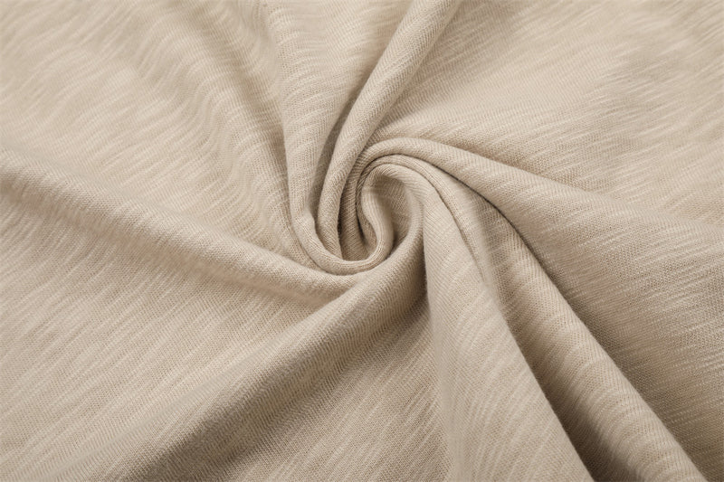 Close-up of beige tee fabric twisted to show soft knit texture
