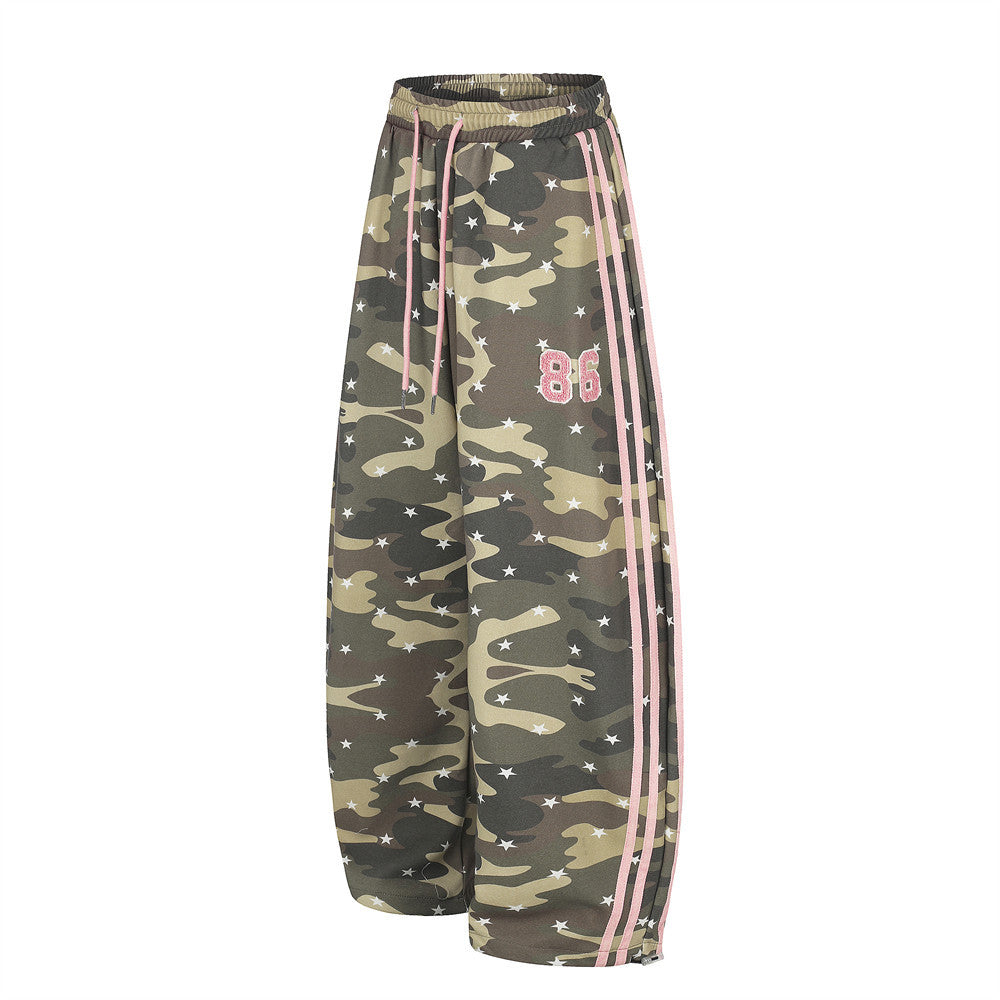 Angled front view of baggy camo pants with pink stripe trim and 86 patch