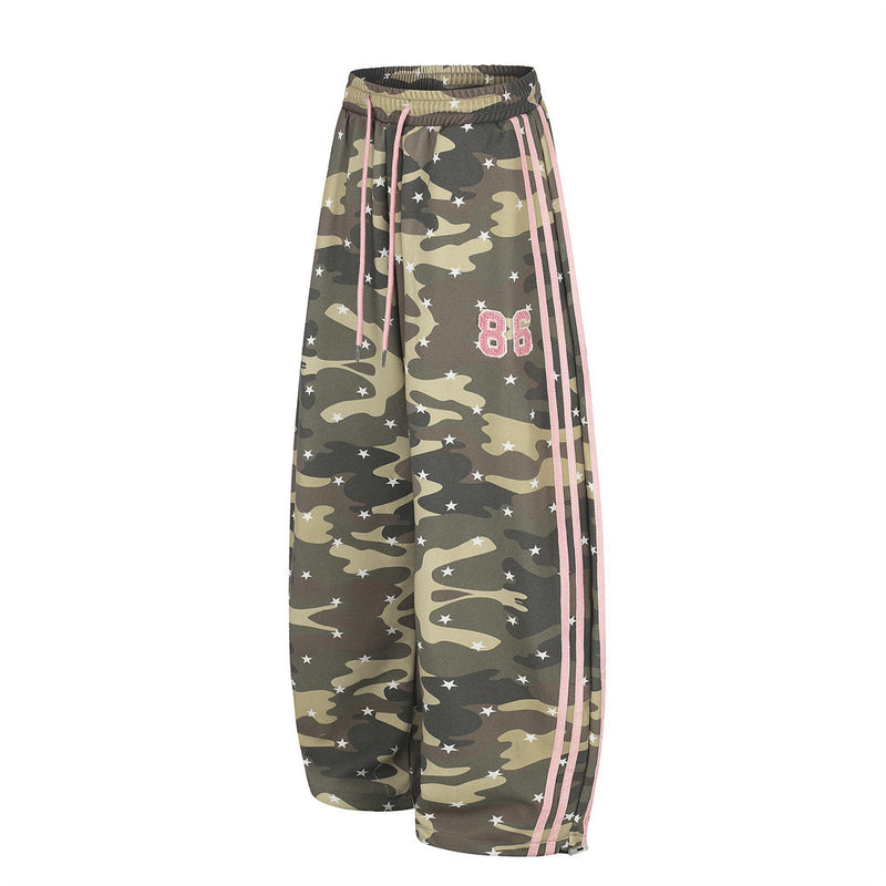 Angled front view of baggy camo pants with pink stripe trim and 86 patch