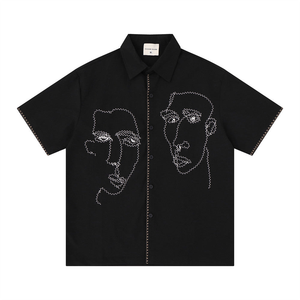 Oversized short-sleeve button-up shirt with abstract face line-art embroidery on front panels, shown in black colorway