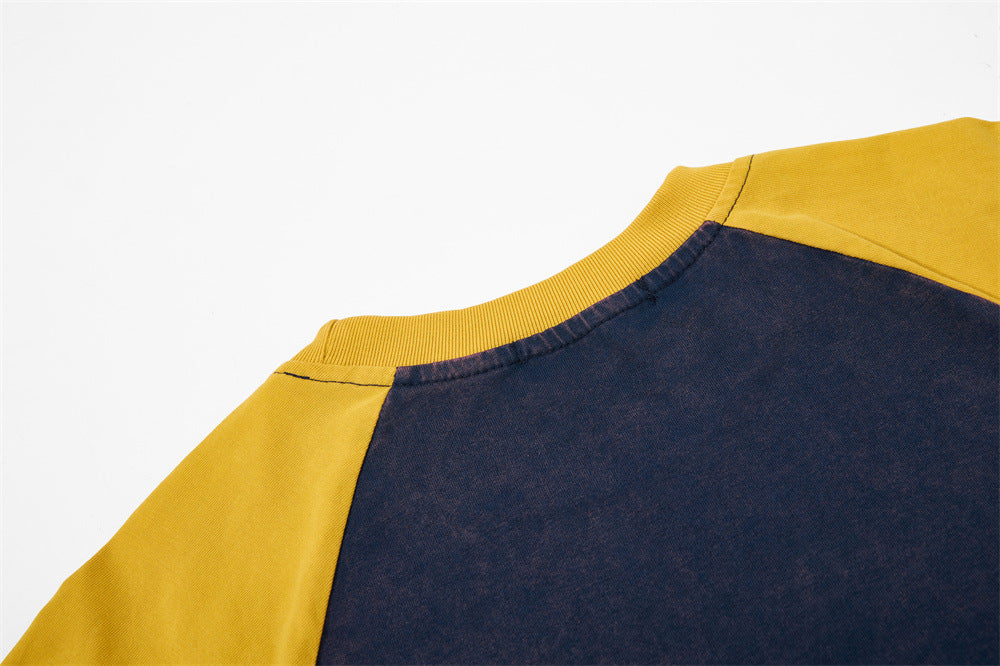Close-up of a vintage raglan colorblock T-shirt in navy and mustard yellow with ribbed crew neckline