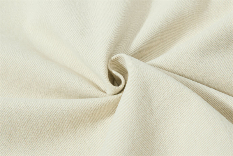 Cream shirt fabric gathered into a spiral, showing soft twill texture