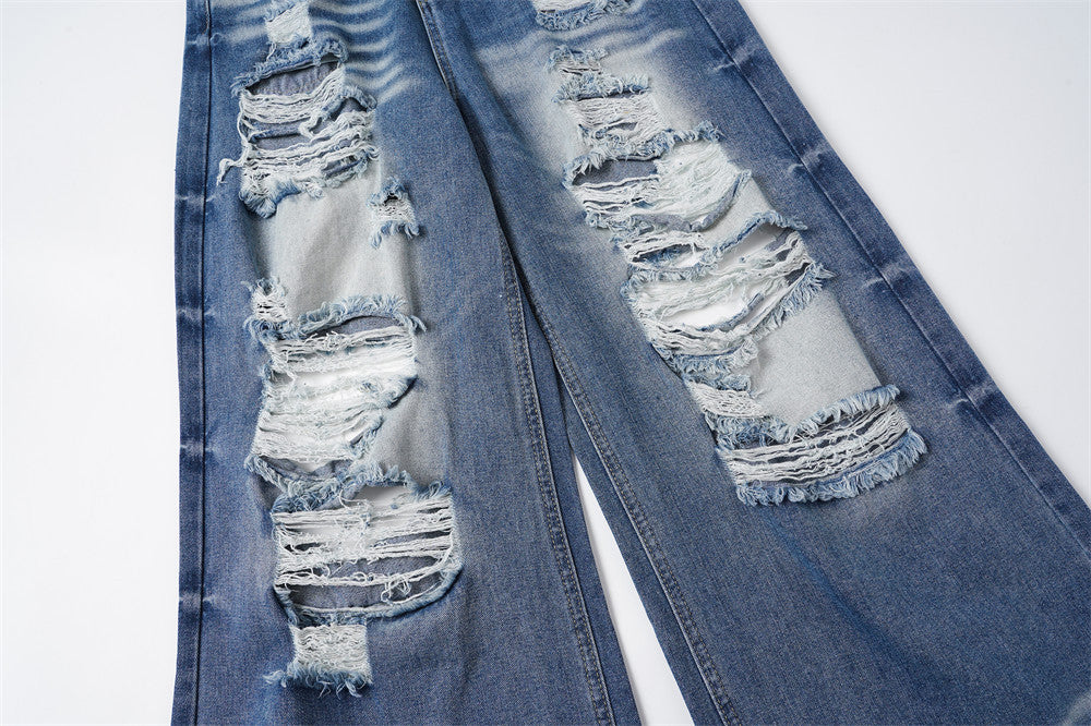 Close-up of ripped denim legs with frayed holes and light fading