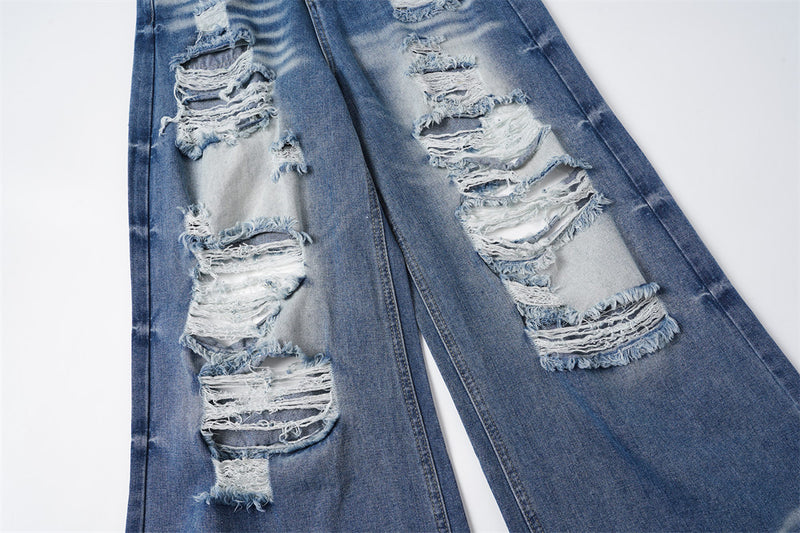 Close-up of ripped denim legs with frayed holes and light fading