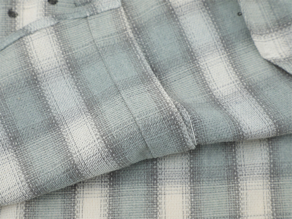 Close-up of folded light gray plaid flannel fabric with visible seam detail