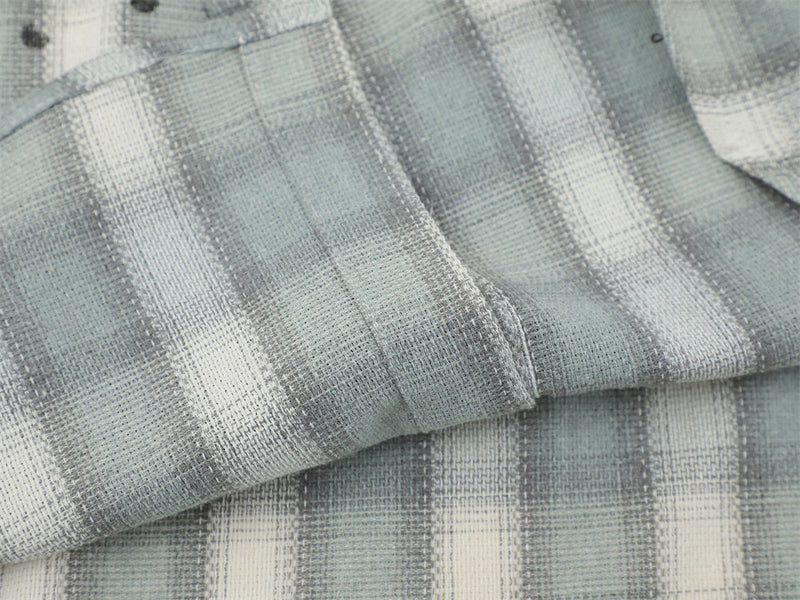 Close-up of folded light gray plaid flannel fabric with visible seam detail