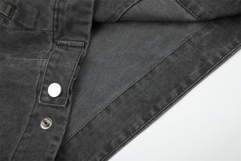 Close-up of black jacket side seam with snap button tab and curved panel stitching