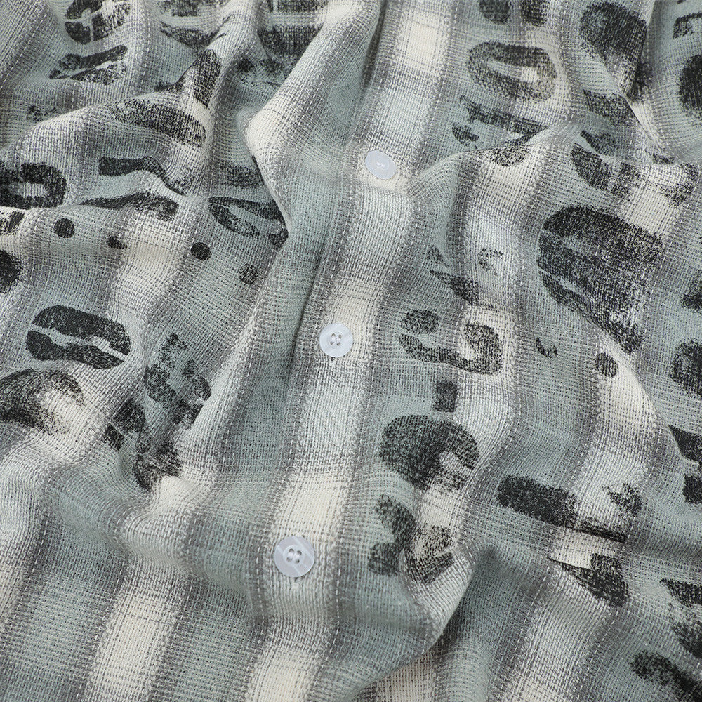 Close-up of distressed black lettering on a light gray plaid flannel shirt