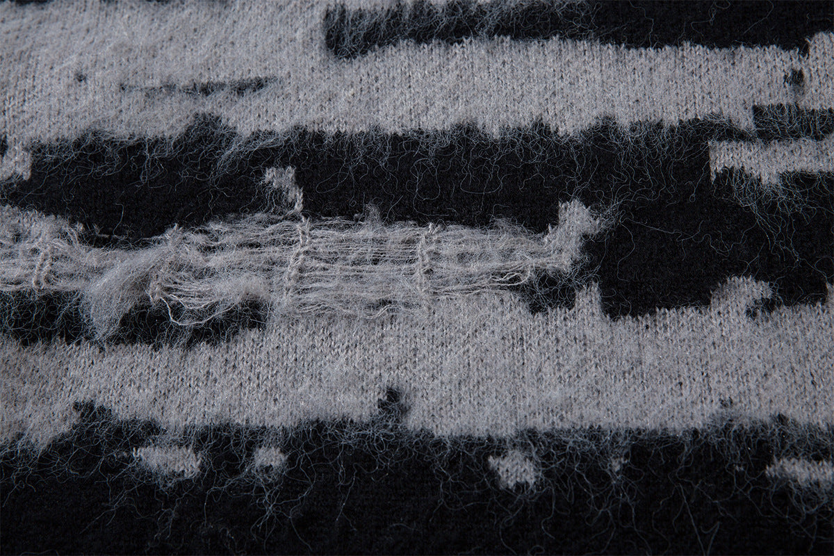 Close-up showing fuzzy black and gray jacquard knit fibers with a distressed horizontal stripe