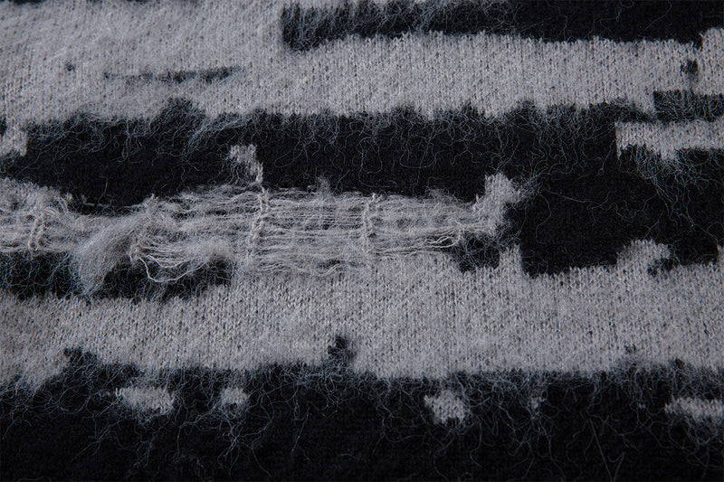 Close-up showing fuzzy black and gray jacquard knit fibers with a distressed horizontal stripe