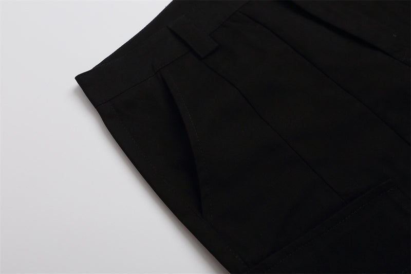 Close-up of black shorts side seam and pocket panel on white background