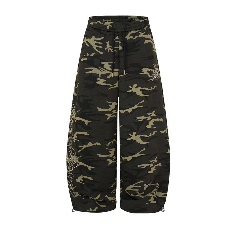 Oversized wide-leg camouflage sweatpants with script graphic print on left leg and drawstring waist, front view