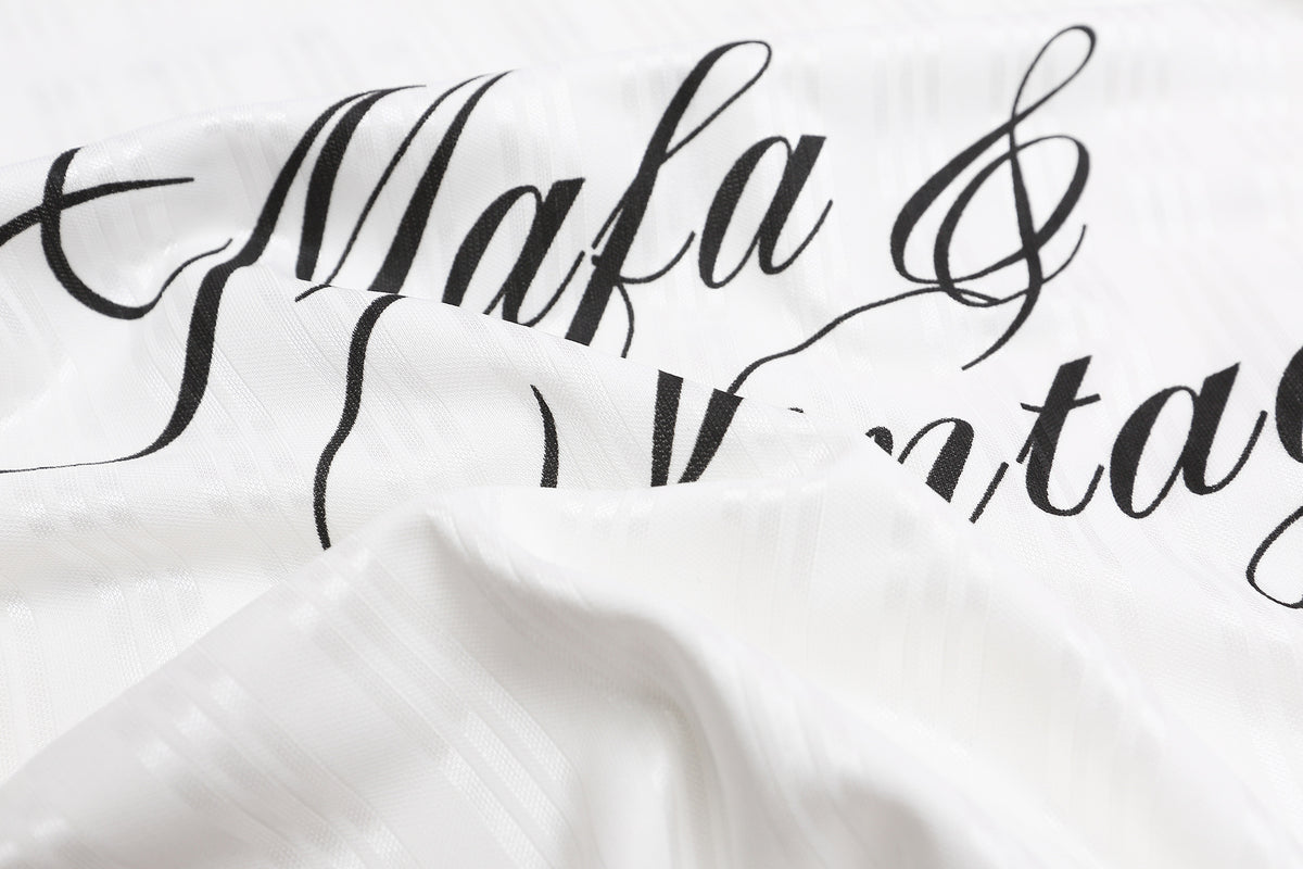 ひだと風合いが見える白いジャージー生地に入った、黒い「Mafa & Vintage」筆記体ロゴのクローズアップ