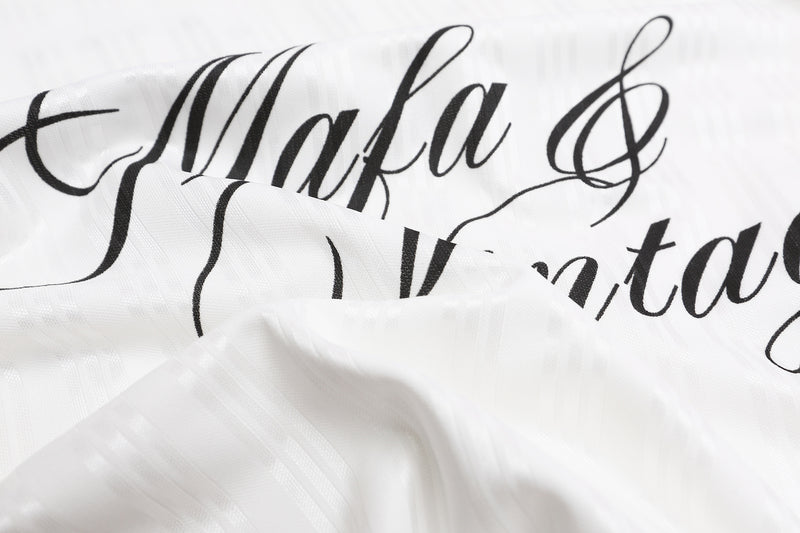 ひだと風合いが見える白いジャージー生地に入った、黒い「Mafa & Vintage」筆記体ロゴのクローズアップ