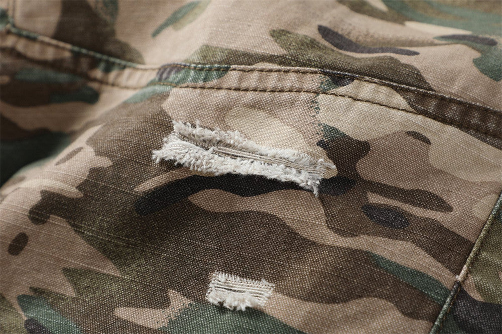 Close-up of distressed camouflage fabric with frayed rip detail