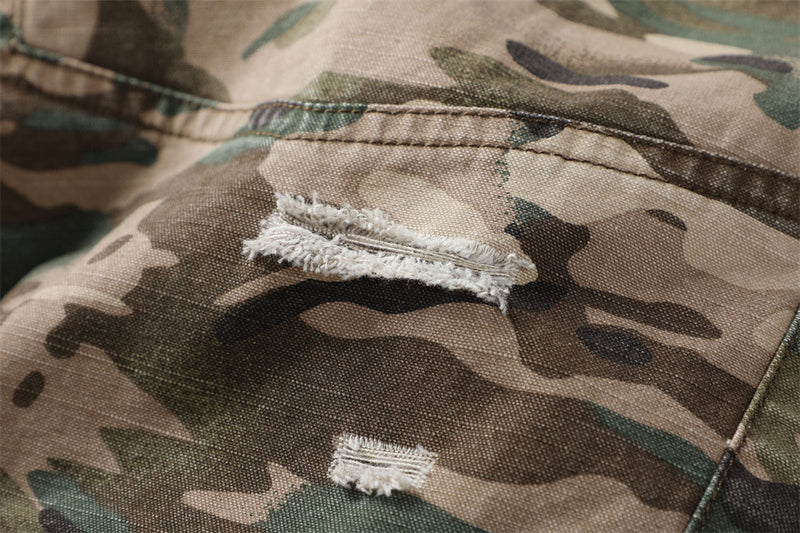 Close-up of distressed camouflage fabric with frayed rip detail