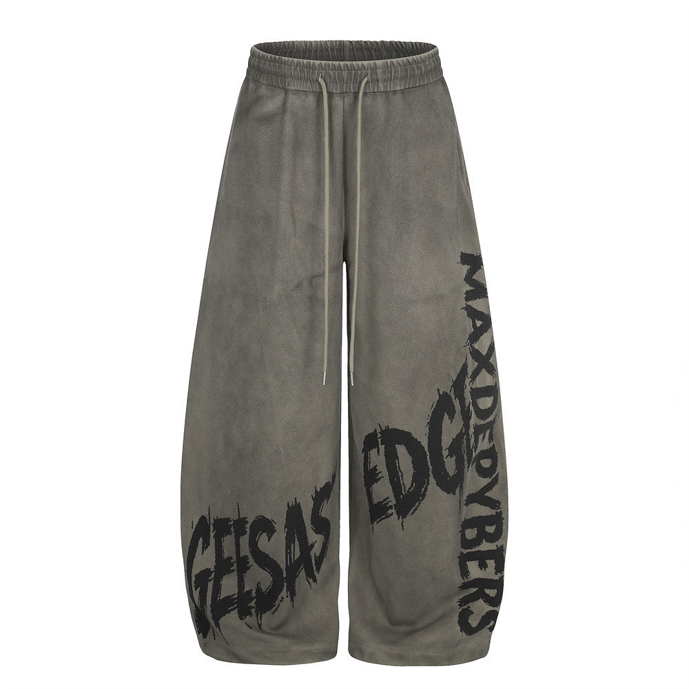 Wide-leg washed gray sweatpants with bold graffiti lettering print across the legs, elasticated drawstring waist, oversized b