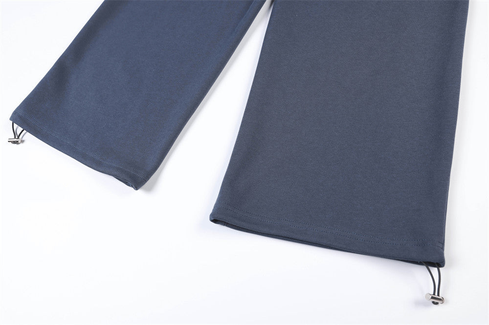 Close-up of wide pant legs and drawstring hems on navy track pants