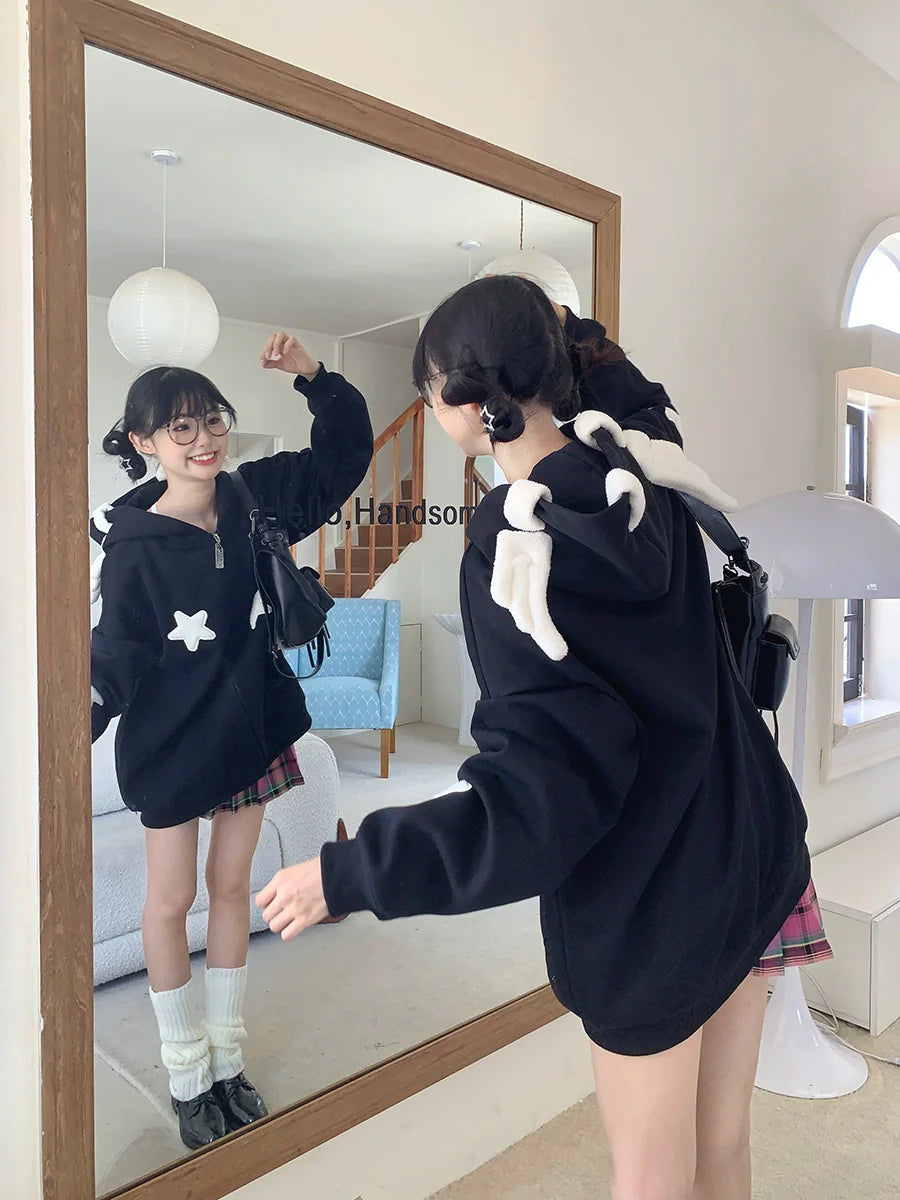 A person stands in front of a mirror, wearing a Seakoff's Kawaii Star Elf Hoodie with 3D ears and star appliques, paired with a plaid skirt and knee-high socks. They have pigtails and glasses, smiling at their reflection in a bright room with whimsical touches like a blue chair and large lamp.