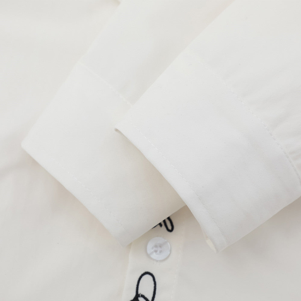 Close-up of white shirt sleeve cuff with embroidered placket edge visible