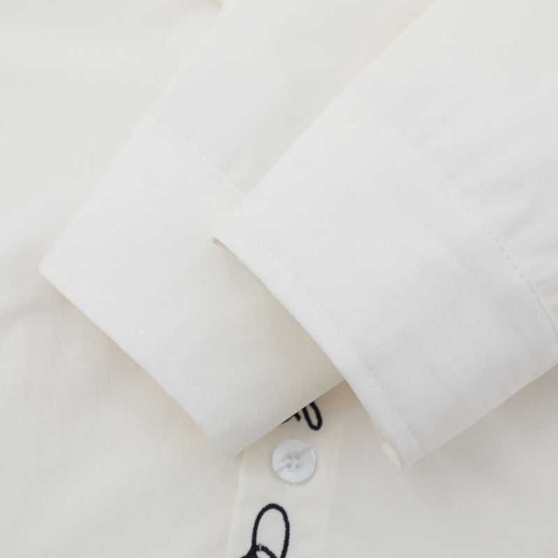 Close-up of white shirt sleeve cuff with embroidered placket edge visible