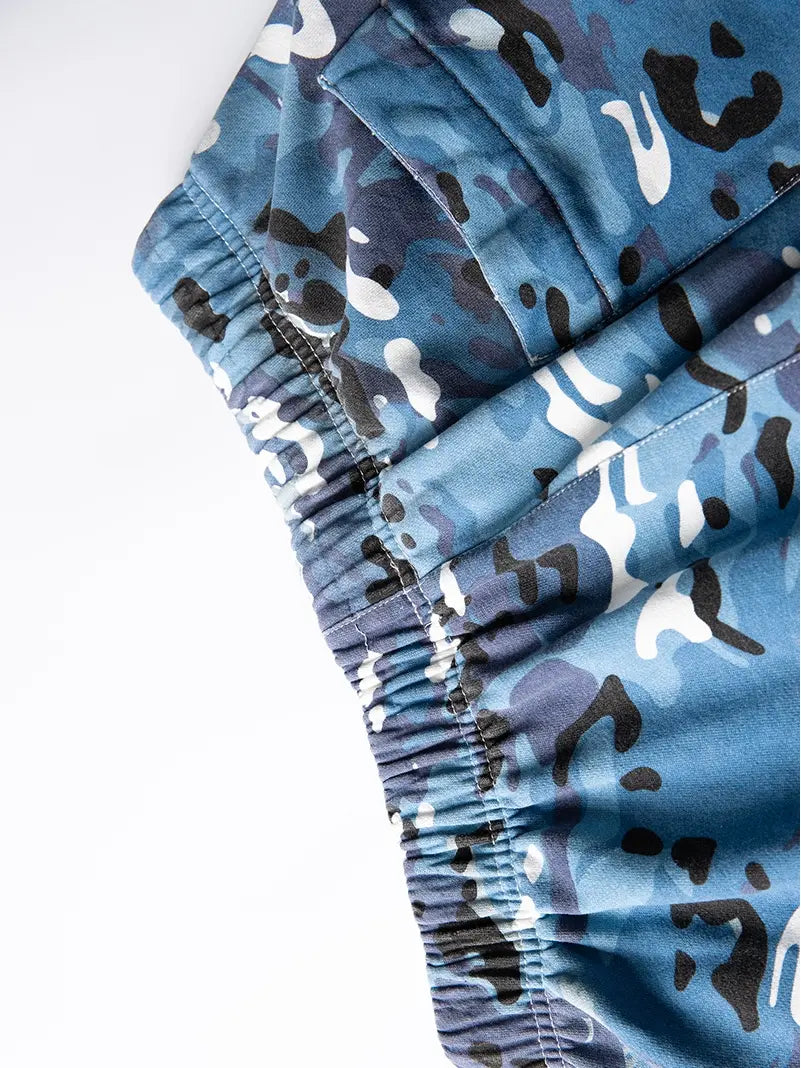 Close-up of Men's Blue Camo Drawstring Shorts—relaxed fit cotton camouflage shorts with elastic waistband and pocket details, shown laid flat on white. Ideal streetwear for a casual look.