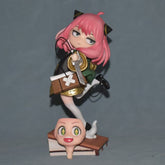 The Anya Forger Cosplay Figure by Spy × Family is a 17.5CM collectible featuring a pink-haired character with horns, dressed in green and gold, holding a gift box. It stands on a detachable head base with white foot, ideal for anime collections or cosplay displays.