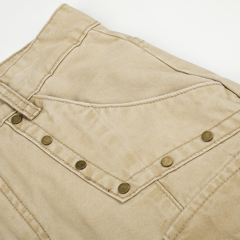 Close-up of beige cargo pants back pocket with stitched flap and metal rivets