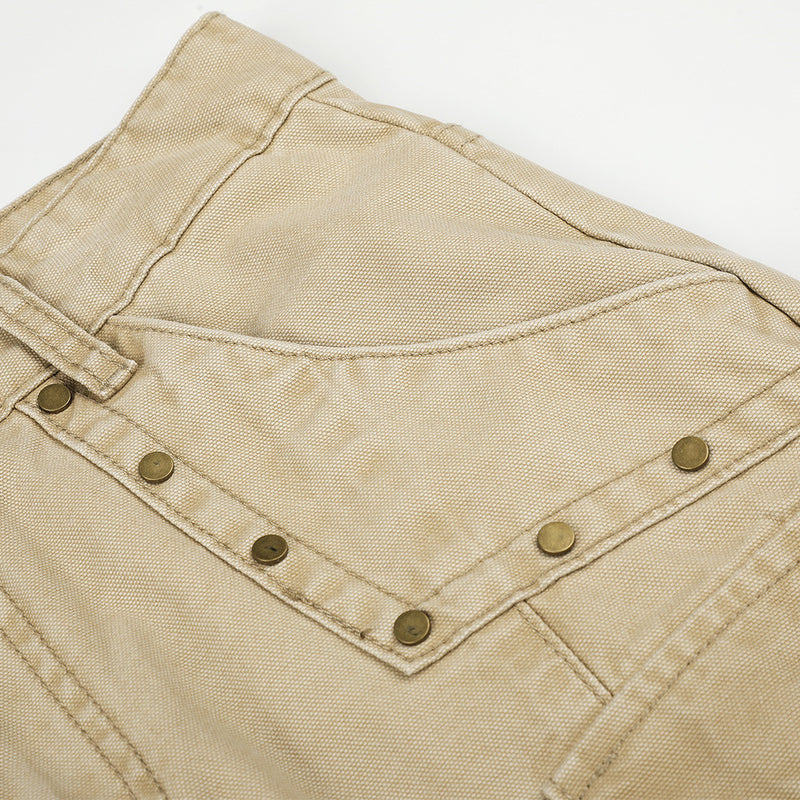 Close-up of beige cargo pants back pocket with stitched flap and metal rivets