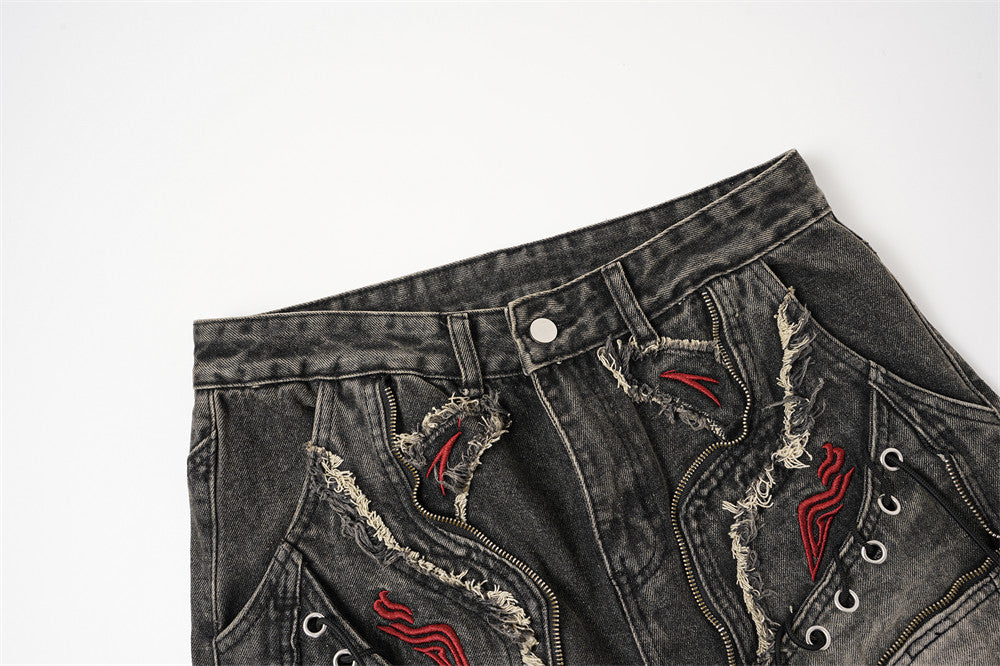 Close-up of the front waistband on black distressed jeans with button closure and frayed patch details