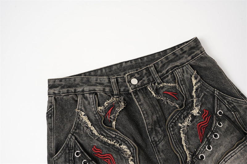 Close-up of the front waistband on black distressed jeans with button closure and frayed patch details