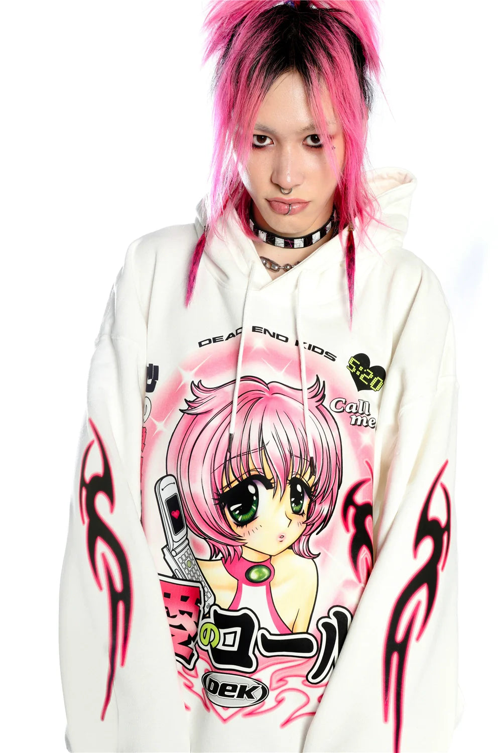 A person sporting bright pink hair and a spiked choker wears Seakoff's Y2K Aesthetic Anime Hoodie, featuring a retro manga girl graphic. It embraces the Y2K look with flame designs on sleeves and bold graphics on a plain white background.