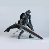 The Berserk Brand Marked Guts Berserker Armor Action Figure is a 16 cm fully poseable PVC statue, featuring a knight in dark armor with a cape and blue-handled large sword, mounted on a transparent stand against a light gray background—perfect for any fan of the series.