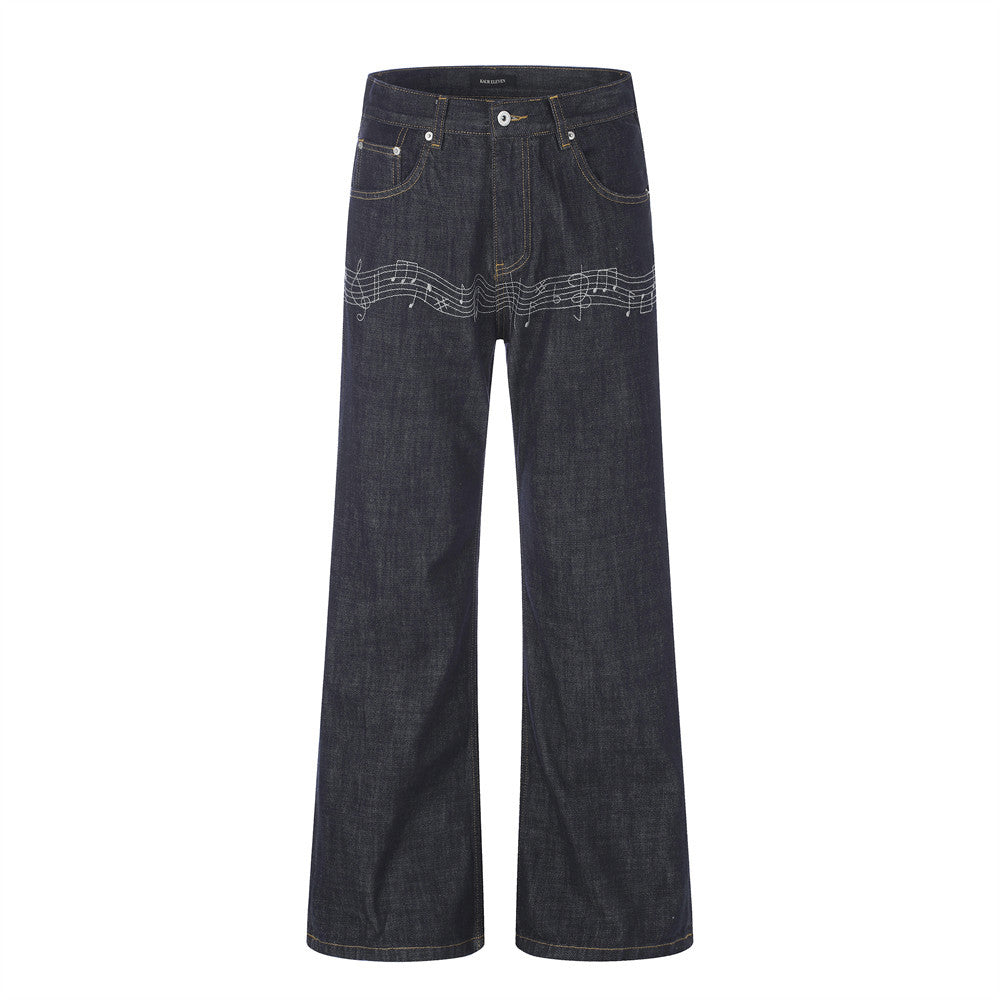 Dark indigo wide-leg raw denim jeans with white embroidered music note and staff detail across the upper leg, front and back