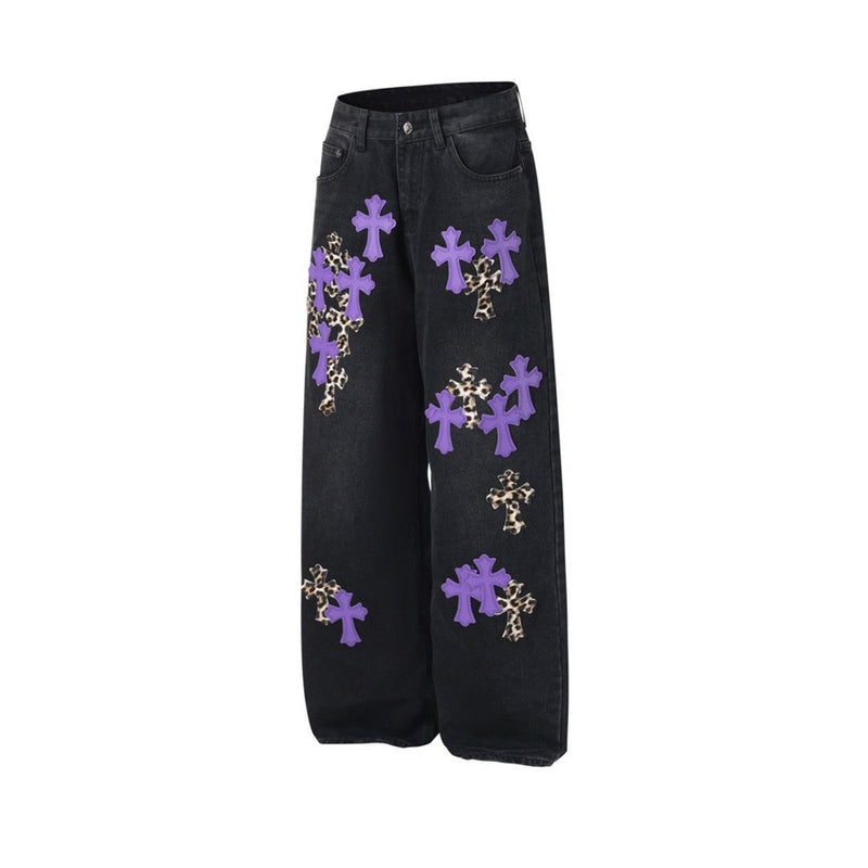 Black wide-leg jeans with purple and leopard cross patches, angled flat lay