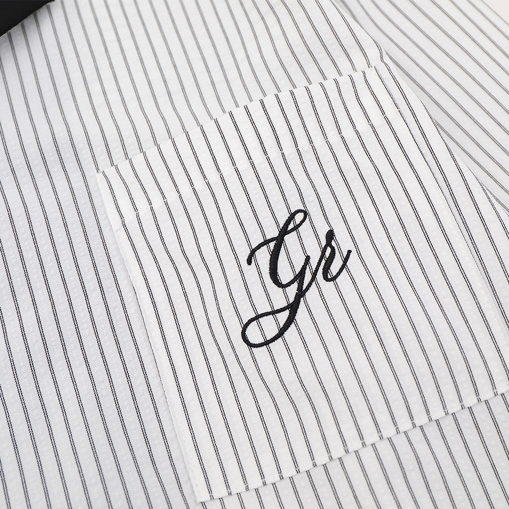 Close-up of chest pocket with script detail on white striped shirt