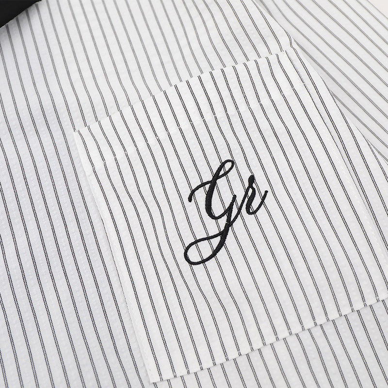 Close-up of chest pocket with script detail on white striped shirt