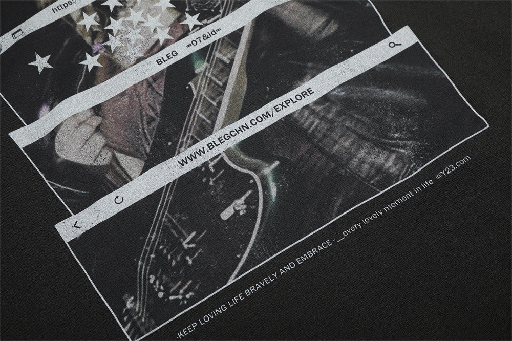 Close-up of lower front print with guitar graphic and website-style text on black fabric