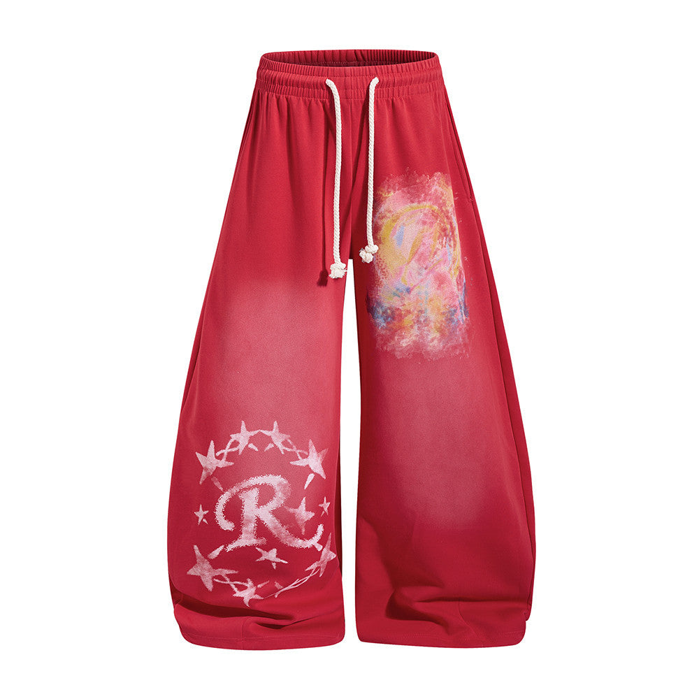Wide-leg sweatpants in red and blue with colorful graffiti print and distressed star logo near hem