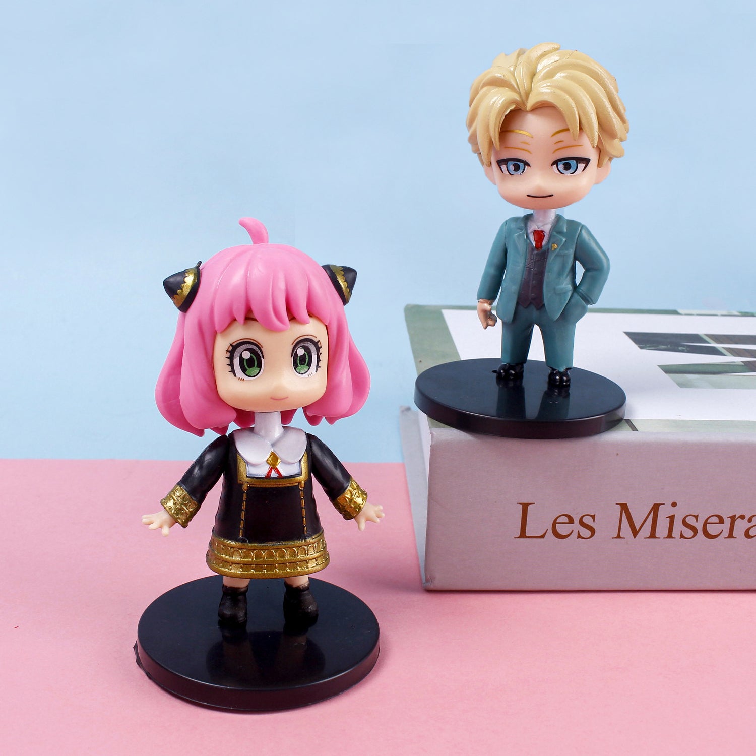 The Spy × Family 6-Piece PVC Figure Set showcases anime-style figures ideal for collectors. Anya has pink hair, cat ears, and a black outfit with gold accents, while Loid sports blond hair and a blue suit. Each figure stands on separate black bases.