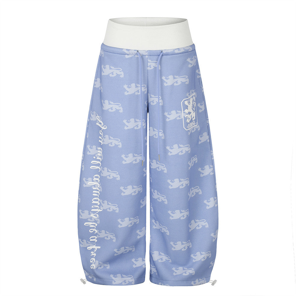 Pantalon de survêtement à jambes larges, imprimé intégral répétitif de lions héraldiques, ceinture côtelée contrastante taille haute et écusson brodé