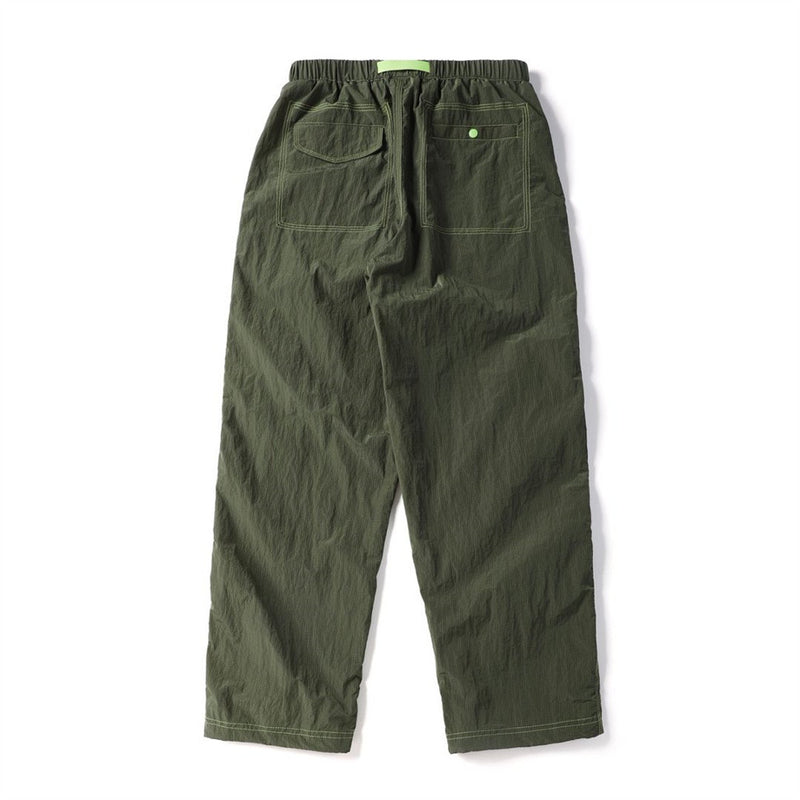 Back view of olive green parachute pants with two rear pockets and contrasting green stitching