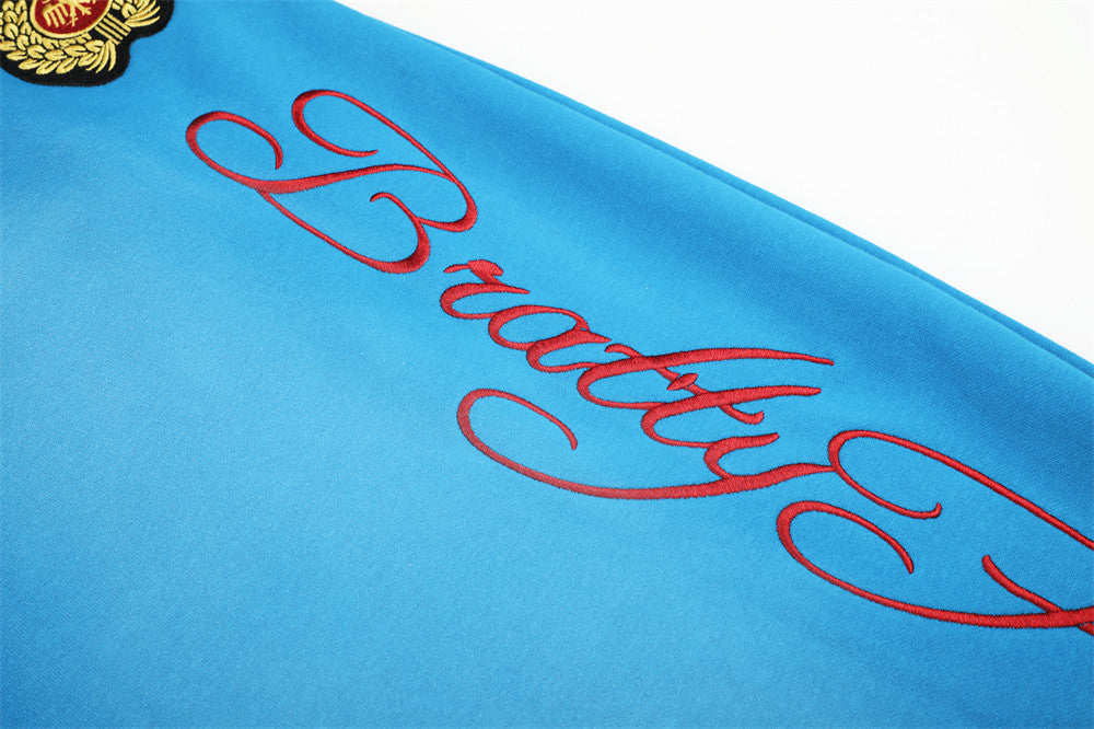 Close-up of red script embroidery on blue sweatpants