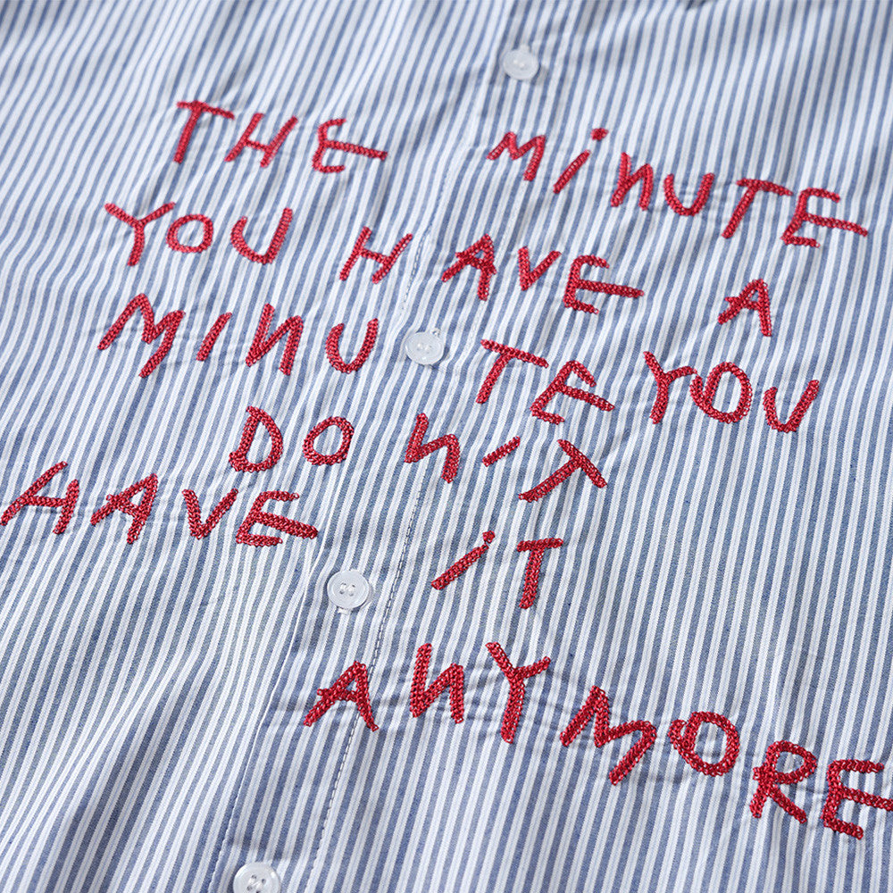 Close-up of red embroidered letter graphic on blue and white striped shirt front