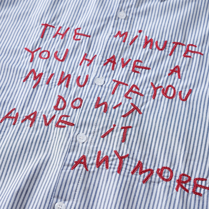 Close-up of red embroidered letter graphic on blue and white striped shirt front