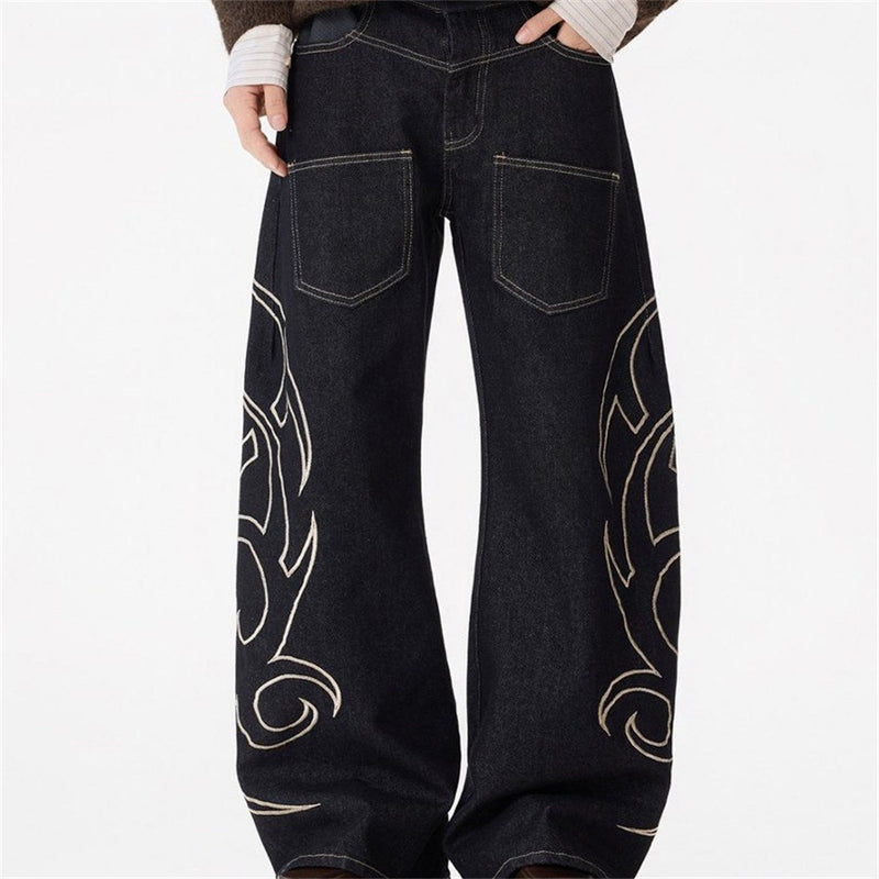 Front view of black wide-leg jeans with pale tribal flame embroidery on both legs