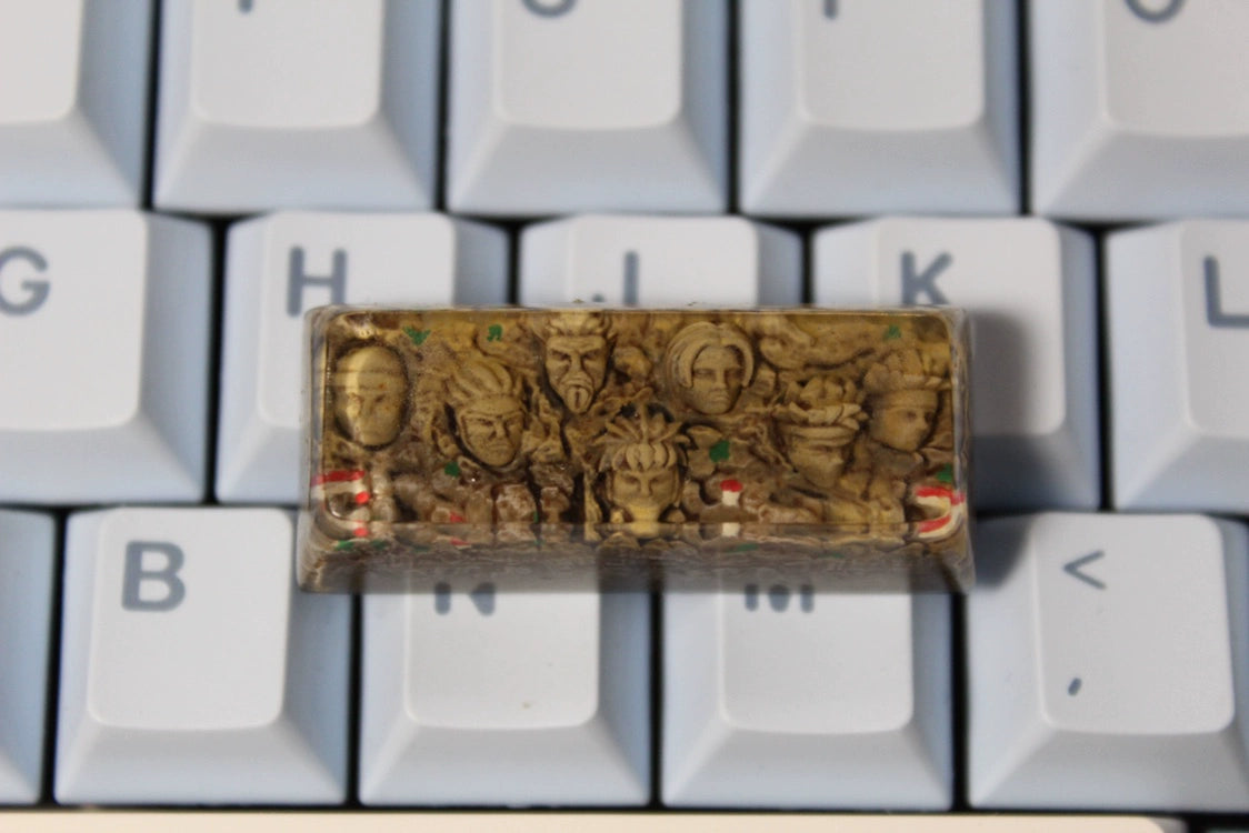 The Hokage Monument Keycap by Naruto, perfect for fans, is a custom spacebar keycap featuring intricately carved Hokage faces for Cherry MX switches. This handmade piece has figurines over light gray keys with white lettering.